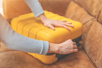 Woman Closing Yellow Suitcase on Couch in House