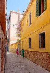 Two girls walking down a picturesque street with flowers in Venice Italy
