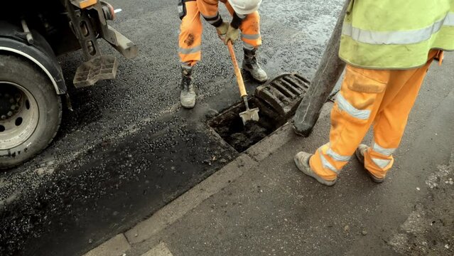 Road workers repairing drain in city street