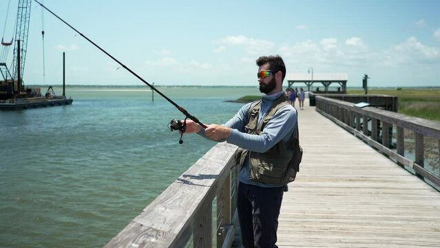 Man salt water fishing on boardwalk pier during the day