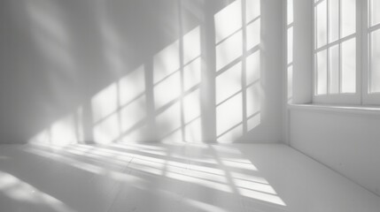A bright room with a large window that casts light and shadows across the white walls and floor.
