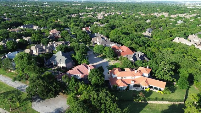 Wealthy suburban neighborhood in lush greenery area with row of expensive mansion houses large backyard, suburbs Dallas Fort Worth metroplex, well-trimmed front yard landscape, Texas, flyover