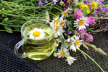 A glass cup with chamomile infusion is on the table.