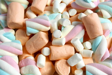 A bunch of different marshmallows lie on a flat surface.
