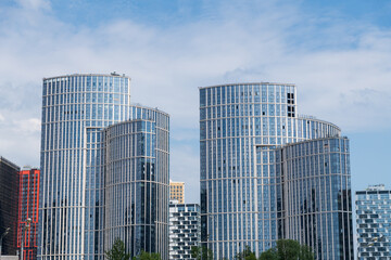 Fototapeta premium Side view of group of modern office or residential buildings in city in a sunny day. Copy space. Blue sky with some clouds. Soft focus. Housing development real estate development theme.