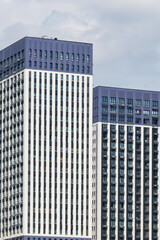 Side view of white and blue residential buildings in a sunny day. Middle section. Copy space. Blue sky with some clouds. Soft focus. Housing development theme.