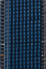 Obraz premium Close-up side view of blue glass wall of modern skyscraper building under construction. Copy space. Abstract construction background. Housing development theme.