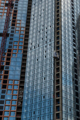 Close-up side view of blue glass wall of modern skyscraper building under construction. Copy space. Abstract construction background. Housing development theme.