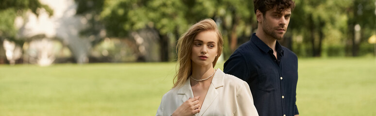 A young couple exudes elegance in a lush green field, embodying old money luxury and a rich lifestyle.