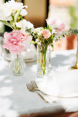 A stunning tabletop is graced by light pink roses and peonies, with exquisite cutlery, creating an elegant setting