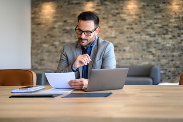 Confident young businessman auditing revenue report and planning budget while working at desk in office