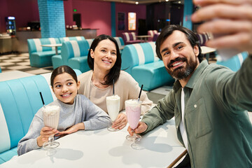 A happy family captures a moment, taking a selfie together at a diner during a weekend outing.