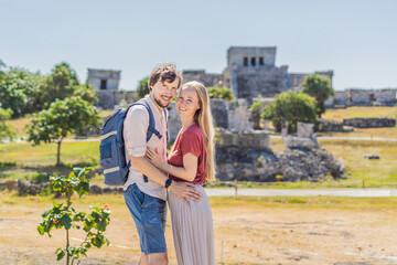Naklejka premium Couple man and woman tourists enjoying the view Pre-Columbian Mayan walled city of Tulum, Quintana Roo, Mexico, North America, Tulum, Mexico. El Castillo - castle the Mayan city of Tulum main temple