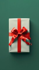 Gift box with red ribbon on green background, close-up. Holiday present and celebration concept