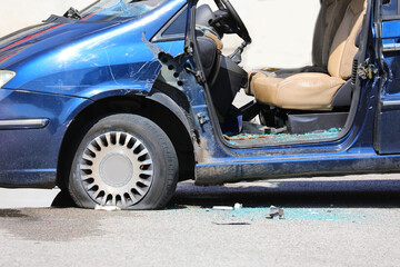 Blue trashed car after rioters vandalized it during city uprising