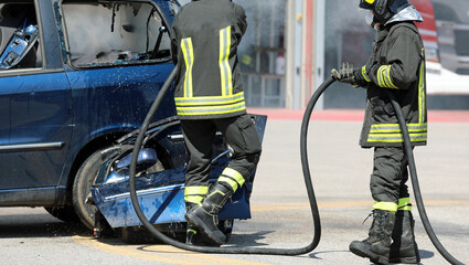Obraz premium firefighters in uniform with helmets extinguish the fire of the wrecked car after the car accident