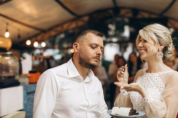 The wedding cake. The bride and groom cut off a piece of cake with a knife. The hands of the newlyweds cut the first piece of the wedding cake.