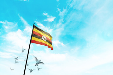 Uganda flag waving with flying doves against sunset or sunrise. Uganda flag for Republic Day and Independence Day.