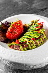Colorful gourmet dish with strawberry, avocado slices, and artistic presentation on a white plate