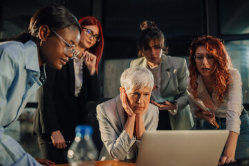 Senior businesswoman nervously looking at report with interracial team