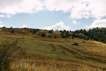 Fototapeta premium Rural landscape with vintage tractor surrounded by green fields and trees in background, agriculture and travel concept