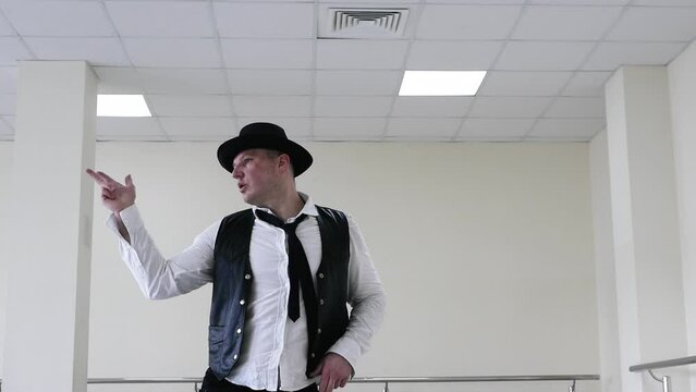 A gangster dances in a hat, a jazzman dances in a tie and vest. Creative dance of a young guy.
