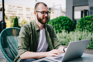 Young hipster boy freelancer using new laptop at favourite cafe learning language by internet, man...