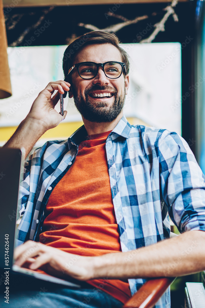 Aufkleber cheerful bearded hipster guy calling on smartphone and laughing during mobile conversation looking o