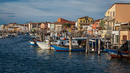 Obraz premium The port coast of the city of Chioggia, boats in the harbor, the architecture of the seaside town, the port with fishing boats, Italy, Veneto.