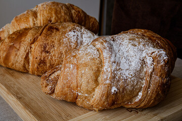 Crispy, fresh, homemade, oven-baked French croissant on a wooden plate; lots of croissants; coffee...