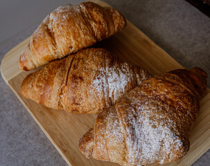 Crispy, fresh, homemade, oven-baked French croissant on a wooden plate; lots of croissants; coffee time; snack; cheat meal
