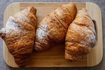 Crispy, fresh, homemade, oven-baked French croissant on a wooden plate; lots of croissants; coffee time; snack; cheat meal