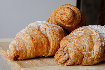 Crispy, fresh, homemade, oven-baked French croissant on a wooden plate; lots of croissants; coffee time; snack; cheat meal