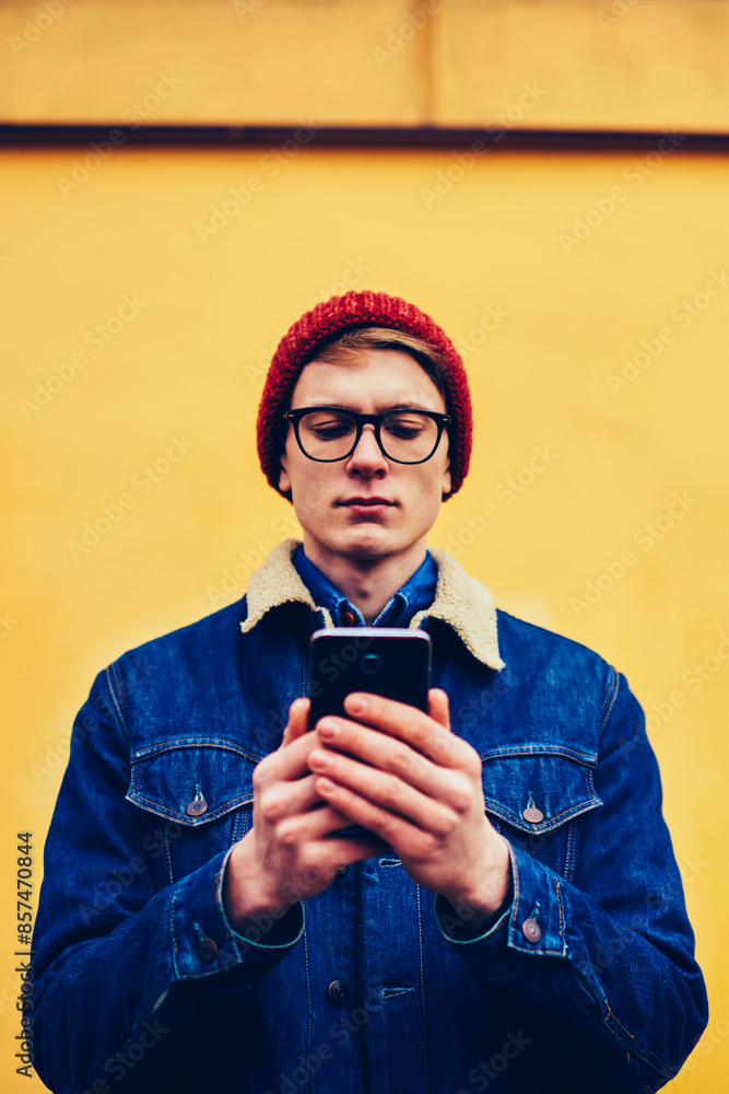 Poster concentrated hipster blogger watching live stream on website via 4g internet connection on smartphon