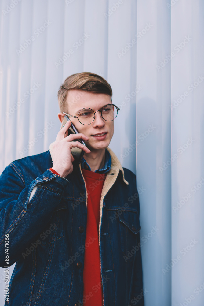 Poster casual dressed young man calling on smartphone and discussing mobile benefits with operator during c