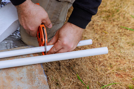 With assistance of special scissors, plumbers cut PVC plastic pipes during installation water pipes