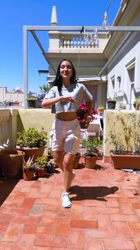 young latin woman dances salsa on the terrace of her house looking on camera
