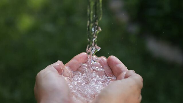 Clean water pours into the palms of the hands. Spring water from nature.