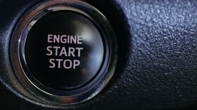 Close-up of finger press  pushing start stop button in car. macro hand starting car with button. Male driver using start button in modern car