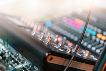 audio mixing console in music production studio, focus on control knobs and cables, with blurred...