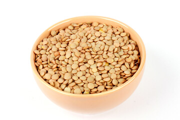Pile of brown raw dry lentils in ceramic bowl isolated on white background