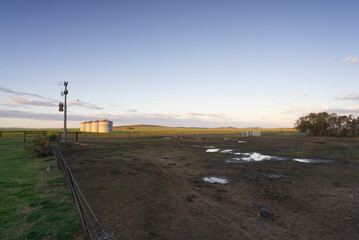 Electricity Supply in Countryside: Rural Electrification Transformer and Silos in a field lanscape © Gabriel