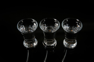 Shots of cold vodka on black background