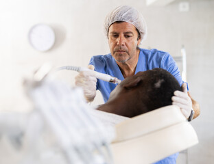 Professional male aesthetician administering hardware procedure on African American adult using ion...