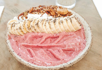 Delicious fruit bowl close-up. Strawberry, bananas, chia seed flour, granola and nuts