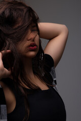 Naklejka premium Beautiful young woman playing with her hair on grey background