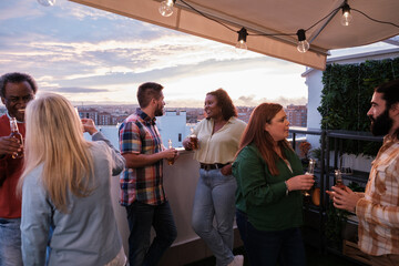 Group of friends enjoying a party on the terrace at sunset. Concept: lifestyle, sharing