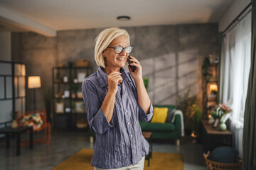 One mature blonde woman stand at home use mobile phone talk