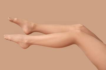 Legs of young woman in nylon tights on beige background