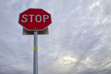 STOP sign isolated against overcast, cloudy sky at dusk, dawn